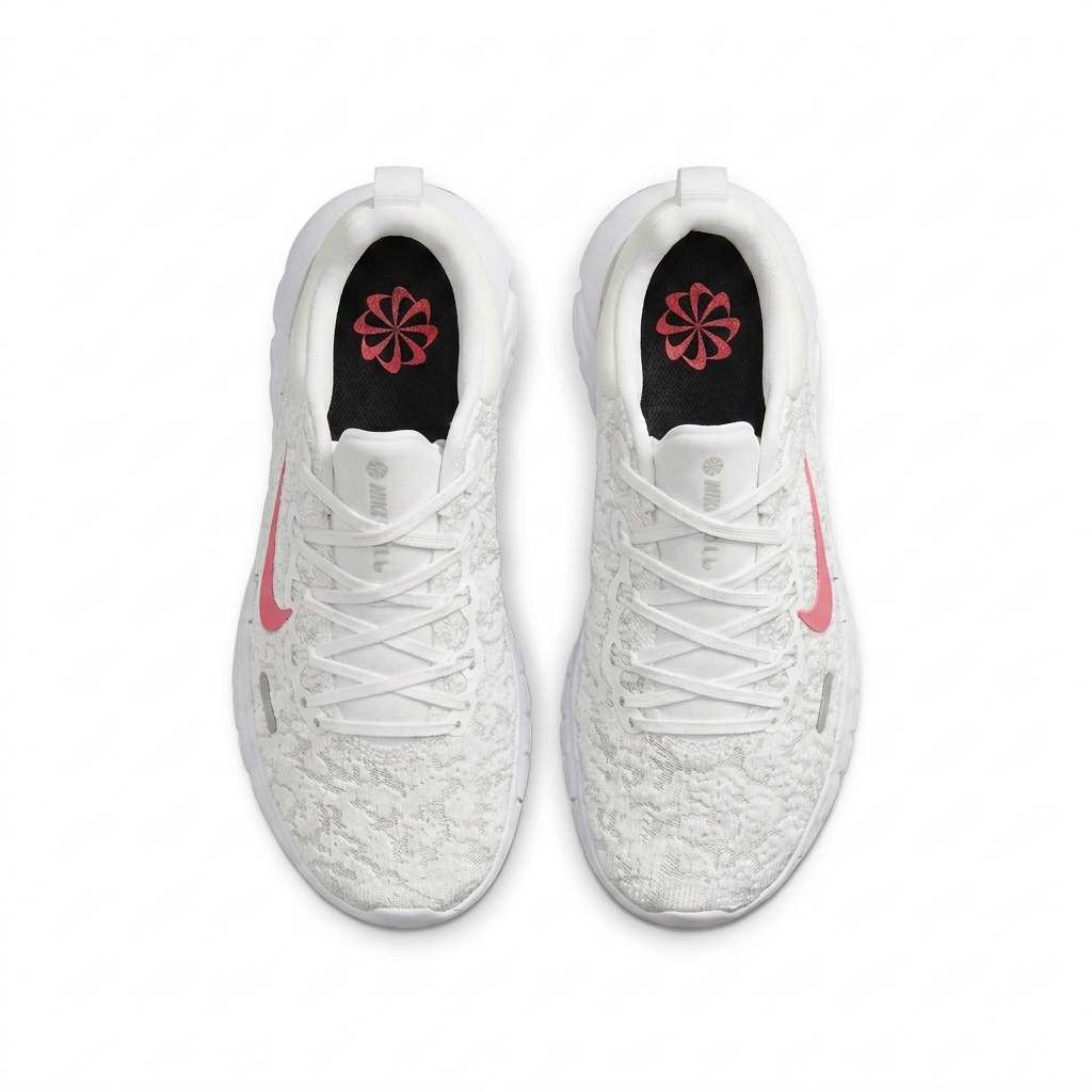 Top view of white Nike sneakers with pink Swooshes and black insoles on white background