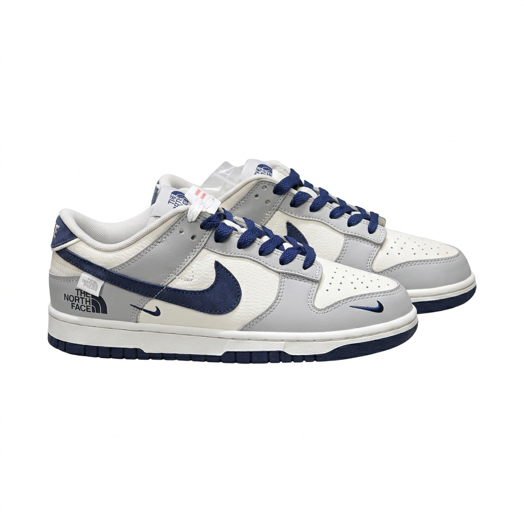 Grey white and navy Nike low-top sneaker pair with printed side lettering, angled view