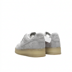 Rear view of light grey Nike low-top sneakers with pale yellow soles on white.