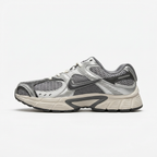 Silver and grey Nike mesh sneaker with cream midsole, side view on white