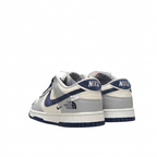Grey white and navy Nike sneakers with NIKE heel tabs, rear angled view on white background