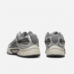 Silver grey Nike sneakers with cream ribbed midsoles, rear view on white