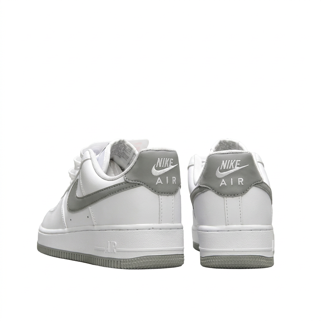 White Nike Air Force 1 sneakers with grey Nike Air heel tabs, rear view on white background