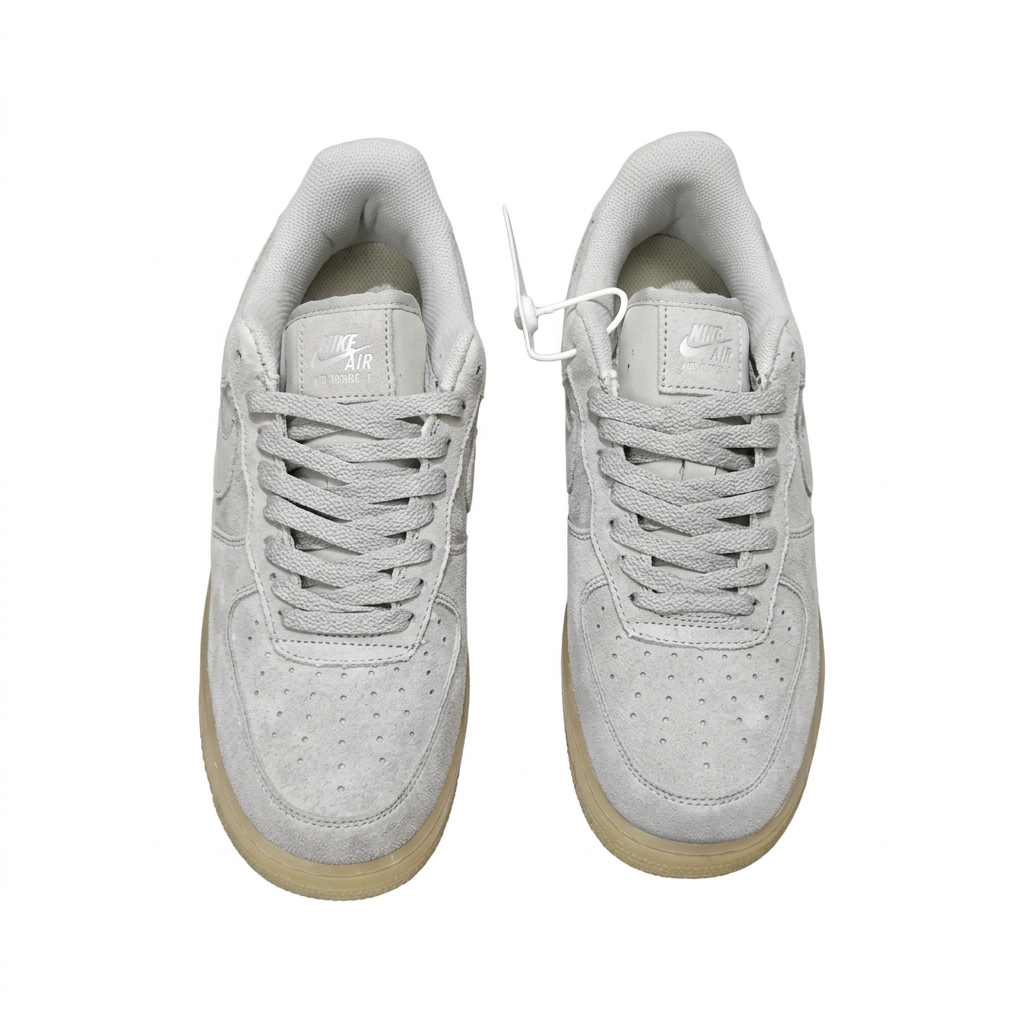Top view of light grey Nike low-top sneakers with matching laces on white.