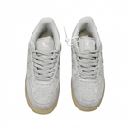 Top view of light grey Nike low-top sneakers with matching laces on white.