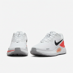 White Nike sneakers with white laces and coral accents, front view on white