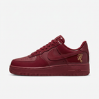Burgundy Nike low-top sneaker with gold details, side view on white