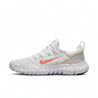 White Nike low-top sneaker with pink Swoosh, side view on white background
