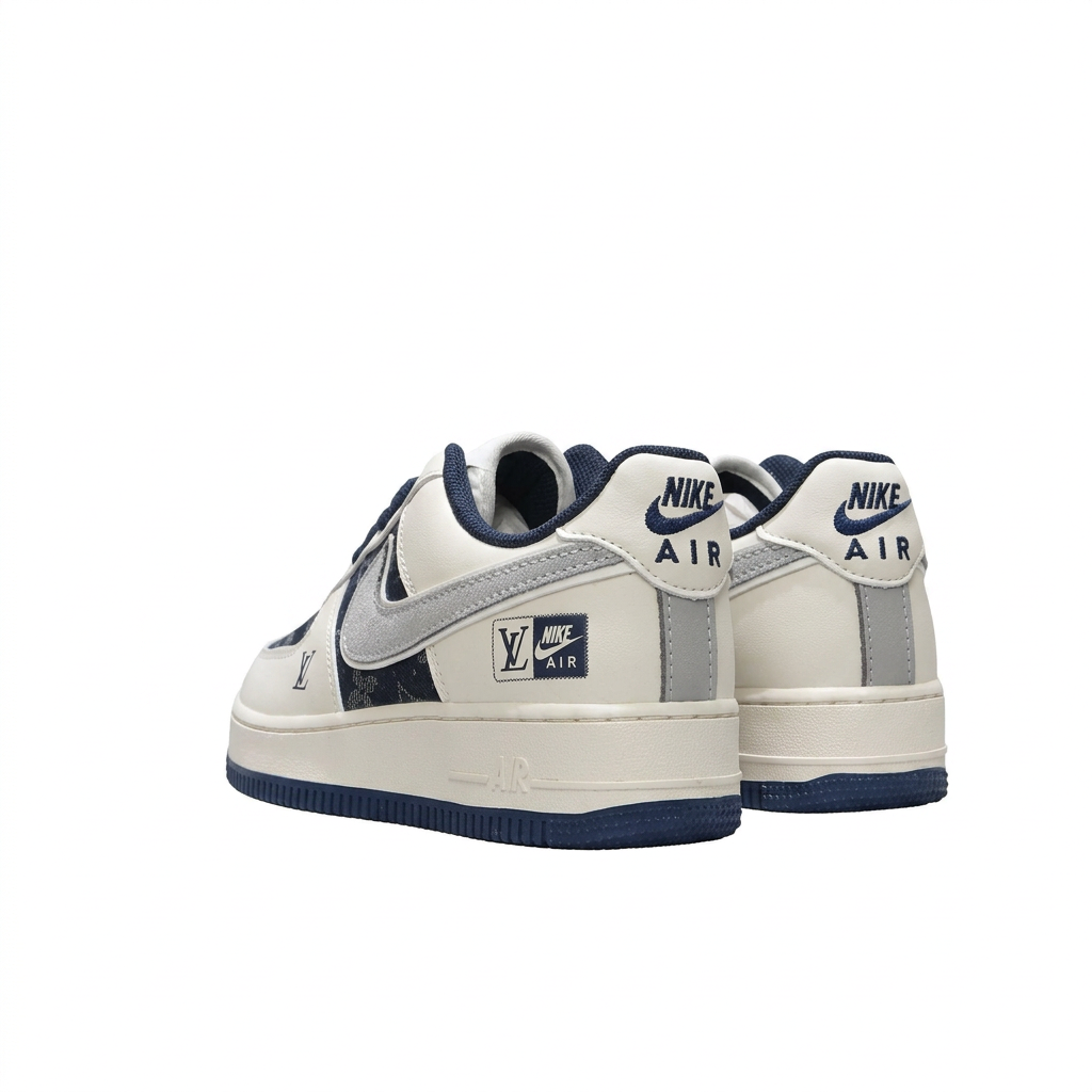 Rear view of cream and navy Nike sneakers with grey Swoosh details and navy soles on white.