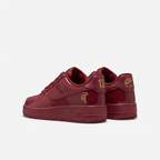 Burgundy Nike sneakers with gold heel details, rear view on white